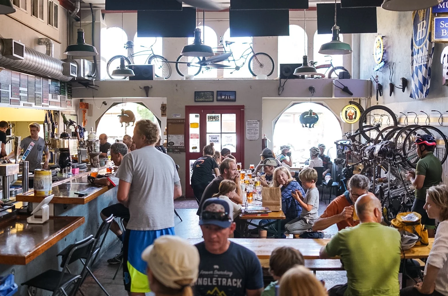 The room at Gestalt Haus — dark walls, bikes on the ceiling, long tables packed with riders